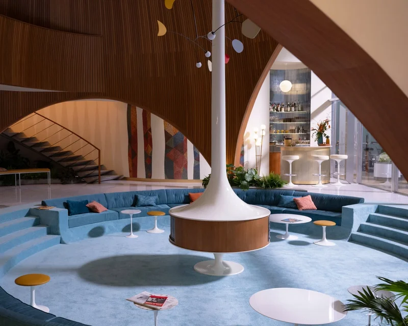 Área de estar rebaixada (conversation pit) com estofados em veludo, inspirada nos anos 70.